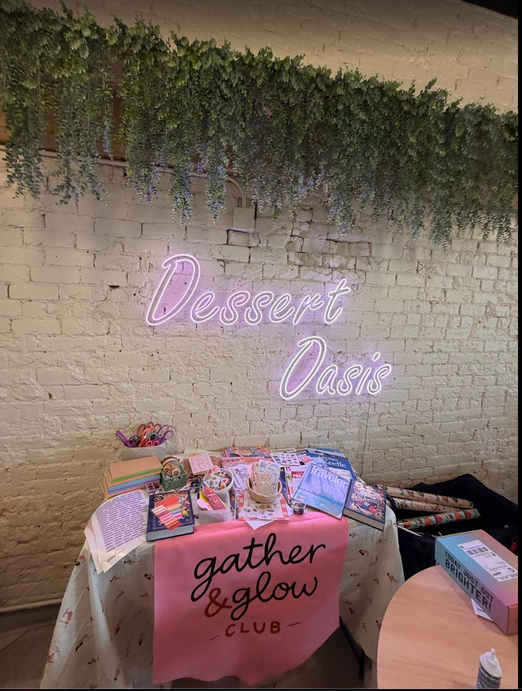 Gather and Glow Club welcome table with craft supplies beneath a Desert Oasis sign